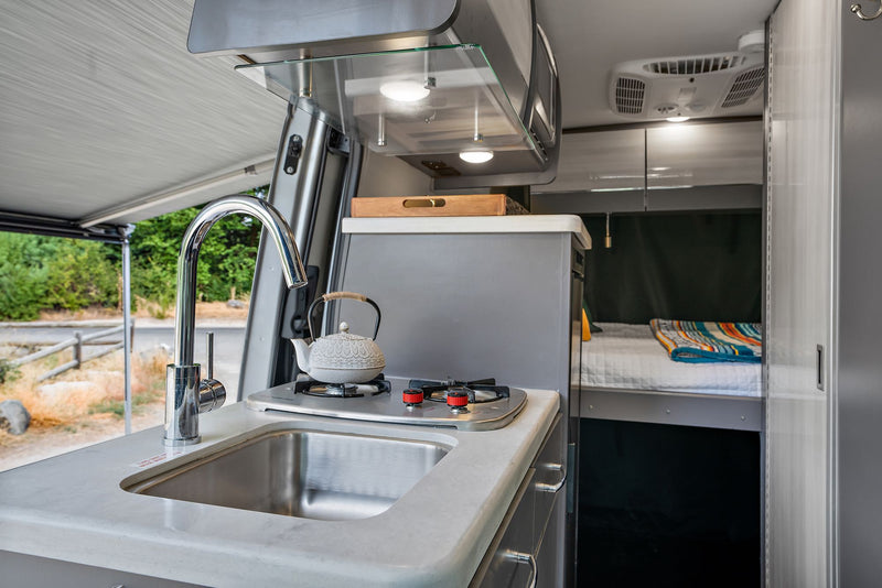  revealing the interior. Chairs & a cooler are set up outside.|Silver Sprinter camper van rv rental with open doors — photo 4