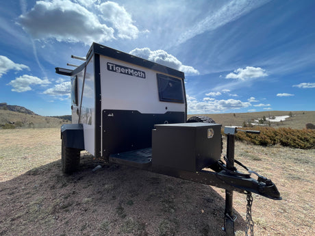 TigerMoth camper trailer, perfect for your next rv rental adventure, parked in a sunny, rugged landscape.