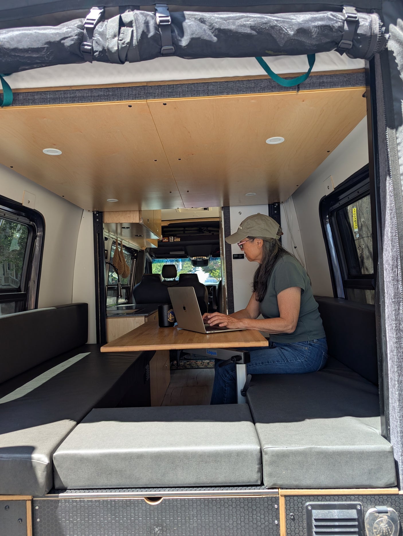 Woman focuses on laptop at a versatile table inside this modern RV rental, a comfy camper van providing a great mobile workspace.