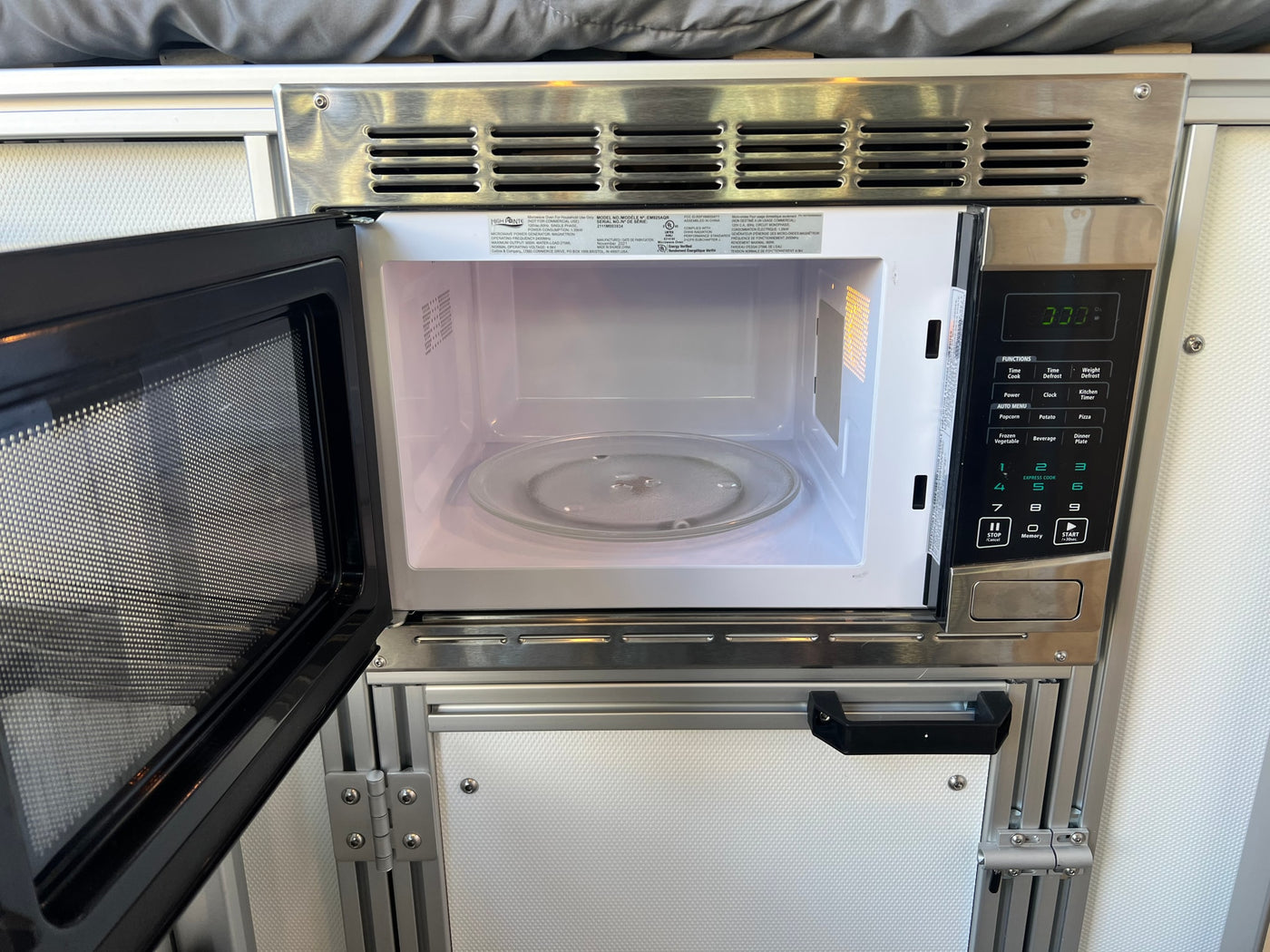Compact microwave oven in an RV rental kitchen, door open, showing its clean interior with a glass turntable and control panel. — photo 12