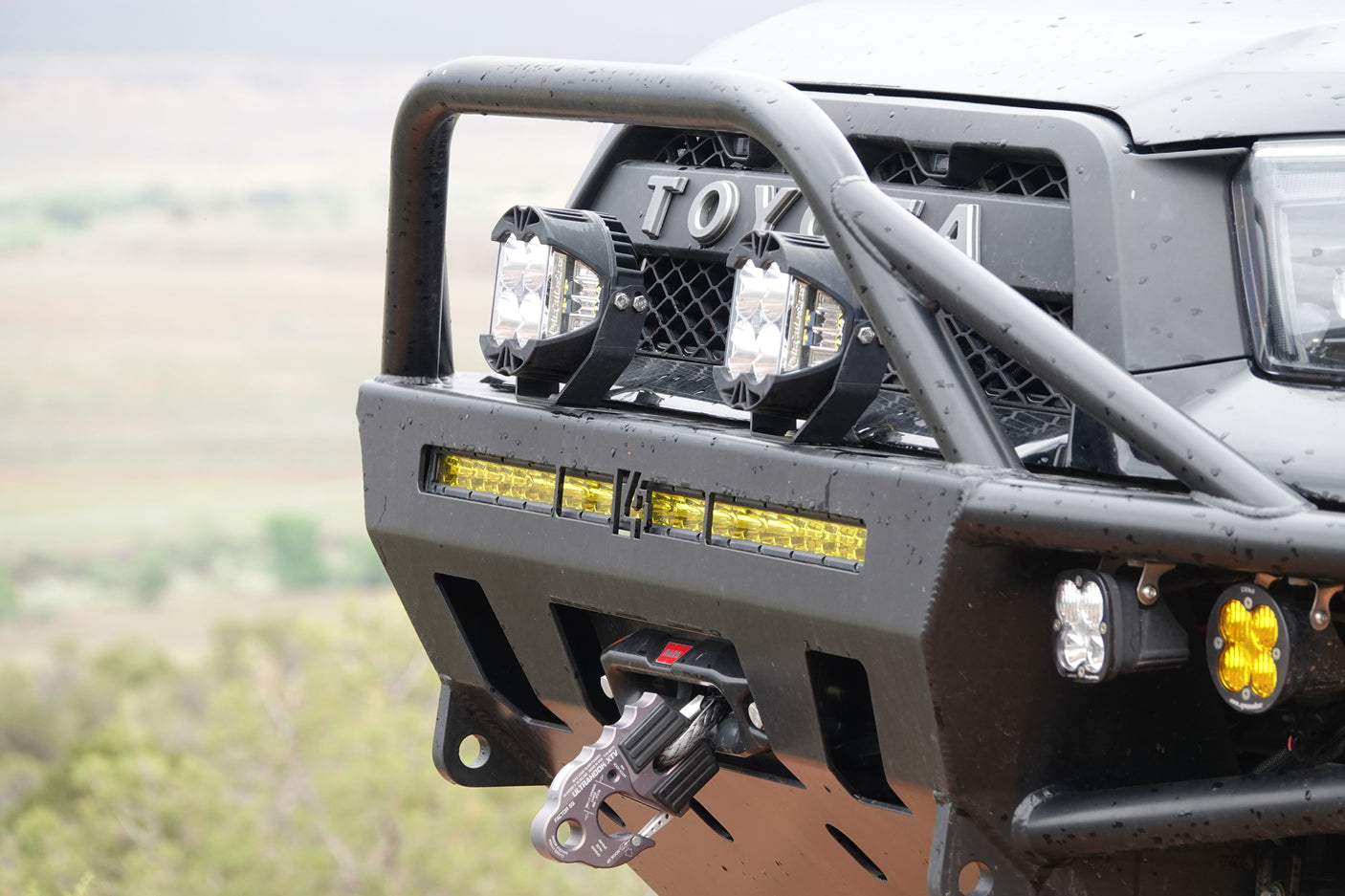 Close-up of a rugged Toyota's front bumper with LED lights, bull bar, and a Factor 55 recovery hook, ready for off-road RV rental fun.