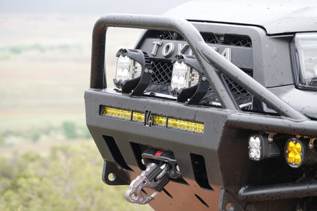 Close-up of a rugged Toyota's front bumper with LED lights, bull bar, and a Factor 55 recovery hook, ready for off-road RV rental fun.