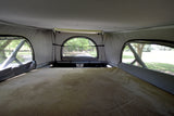 Cozy pop-top bed in an RV rental, offering serene views through mesh windows. Ideal for nature lovers.