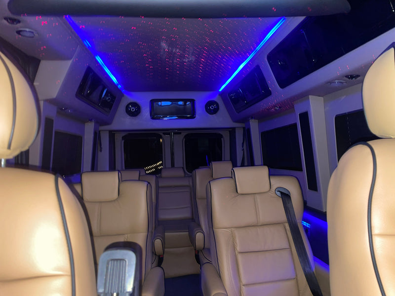 Inside a spacious RV rental: tan leather captain's chairs, a starry night ceiling, and ambient blue LED lighting. — photo 12