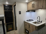 RV rental: modern kitchen with stove, sink, microwave, fridge, plus bunk beds and a cozy fireplace.
