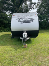 This silver Wolf Pup travel trailer is ready for your next adventure. Consider this RV rental parked on lush green grass.