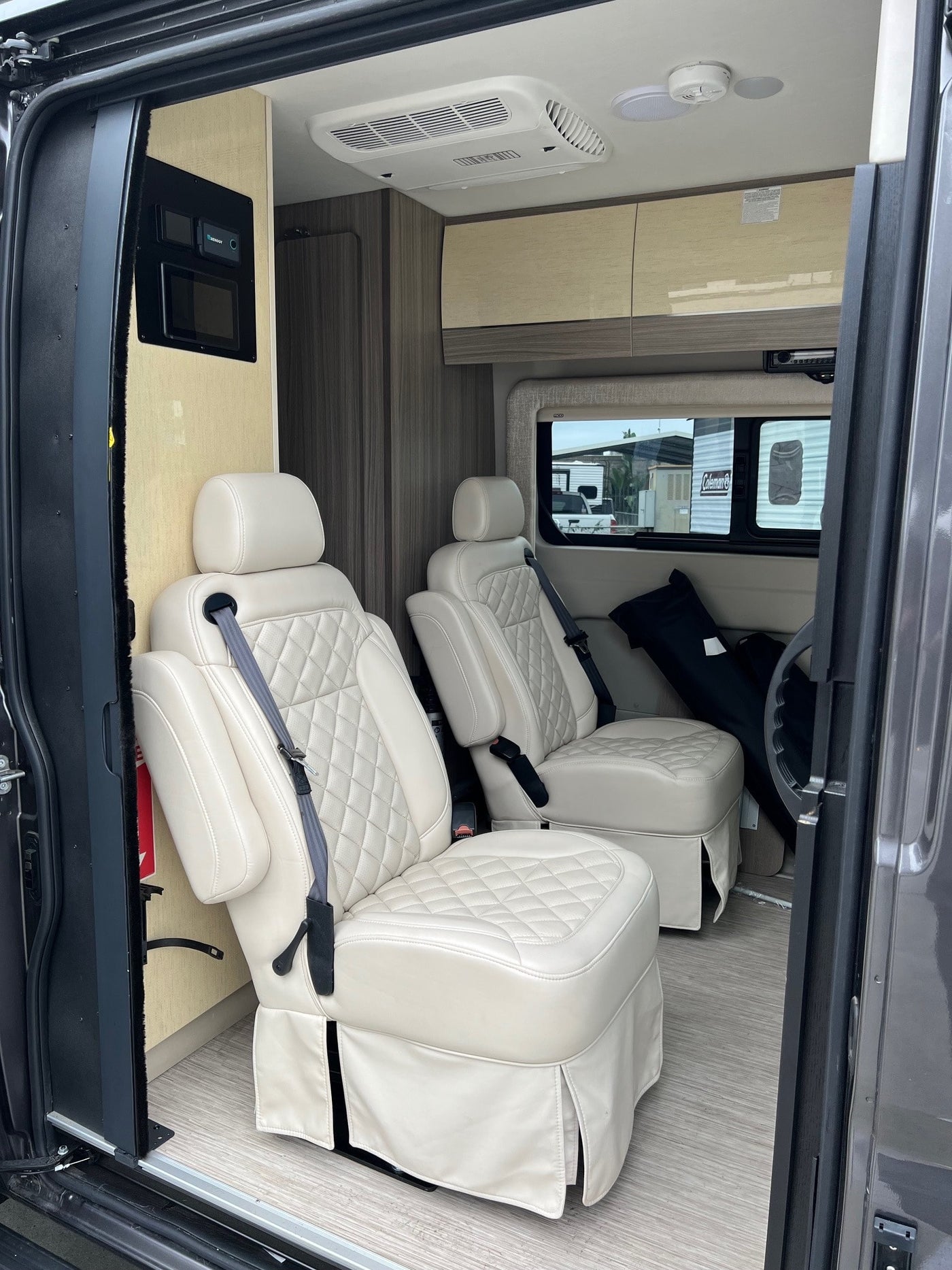 Luxury RV rental interior with cream captain's chairs, control panel, and overhead cabinets. — photo 5