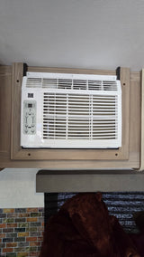 White RV rental AC unit with digital and button controls for temp, fan, & modes, set in wooden cabinetry for RV climate comfort.
