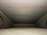 Pop-top RV rental interior: a comfy mattress and fabric walls, with small ceiling lights, ready for your adventure.