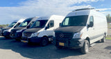 A fleet of white Mercedes-Benz Sprinter vans, ready for adventure as RV rentals, parked in a row on a sunny day.