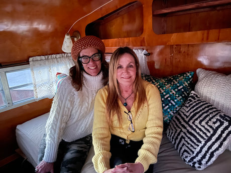 Two smiling women enjoying their cozy RV rental interior, perfect for travel adventures.