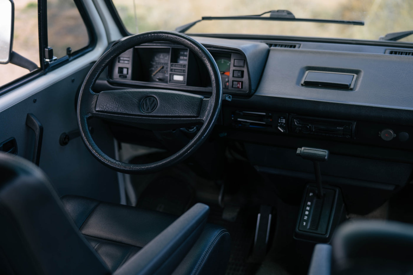  and desert views.|RV rental: View from a camper van showcasing a vast desert landscape filled with Joshua trees and distant mountains.|Inside a classic VW campervan: steering wheel — photo 3