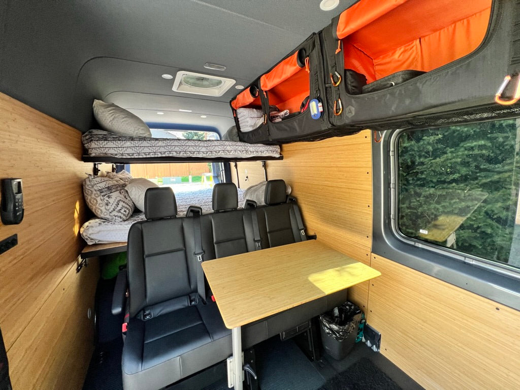 Experience comfort in this RV rental: bunk beds, rear seats, dining table, and overhead storage visible.