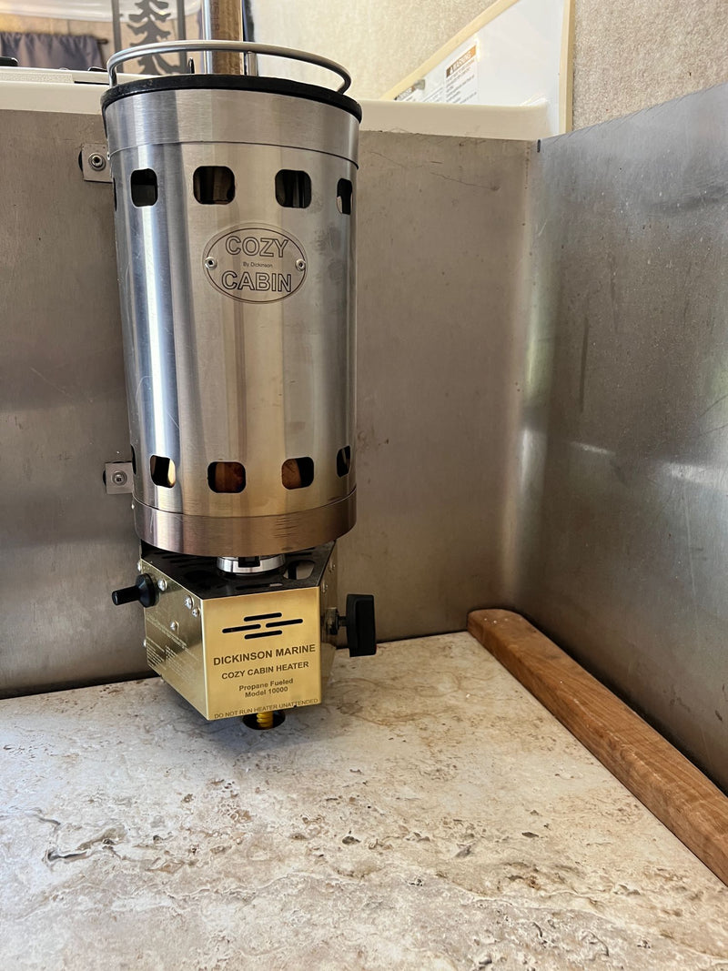 A Dickinson Marine Cozy Cabin propane heater, Model 10000, installed in an RV rental. Stainless steel unit on a counter. — photo 20