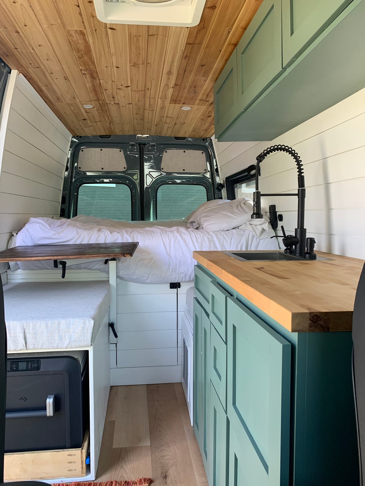  and sage green cabinets.|Stylish rv rental camper van interior featuring a comfortable bed — photo 5