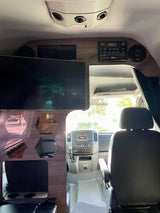 RV rental interior shows a large TV, stereo, speakers, and hexagonal wall decor, with a clear view of the dashboard and front cabin.
