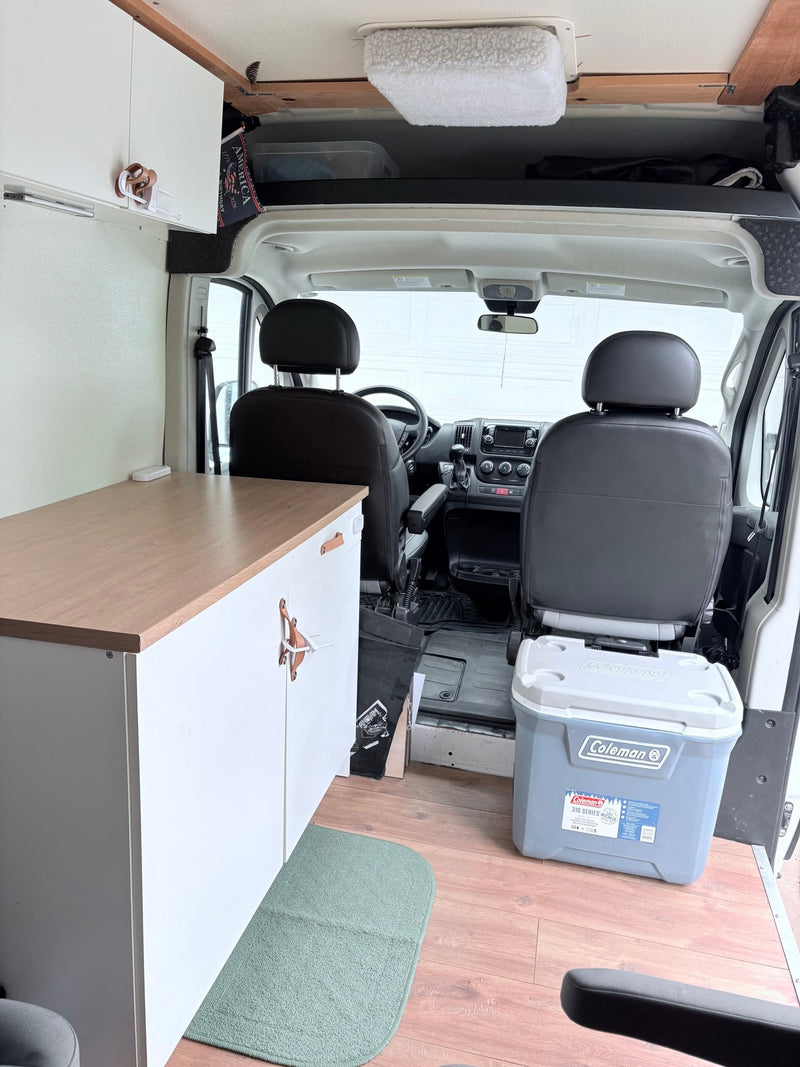 Inside this rv rental: a cozy camper van featuring light wood cabinetry, flooring, and a Coleman cooler for mobile living. — photo 6