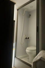 Compact RV rental wet bath with shower, toilet, and glass enclosure.