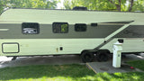 This rv rental, an Open Range travel trailer, is parked at a tree-lined campsite with utility hookups for power and water.