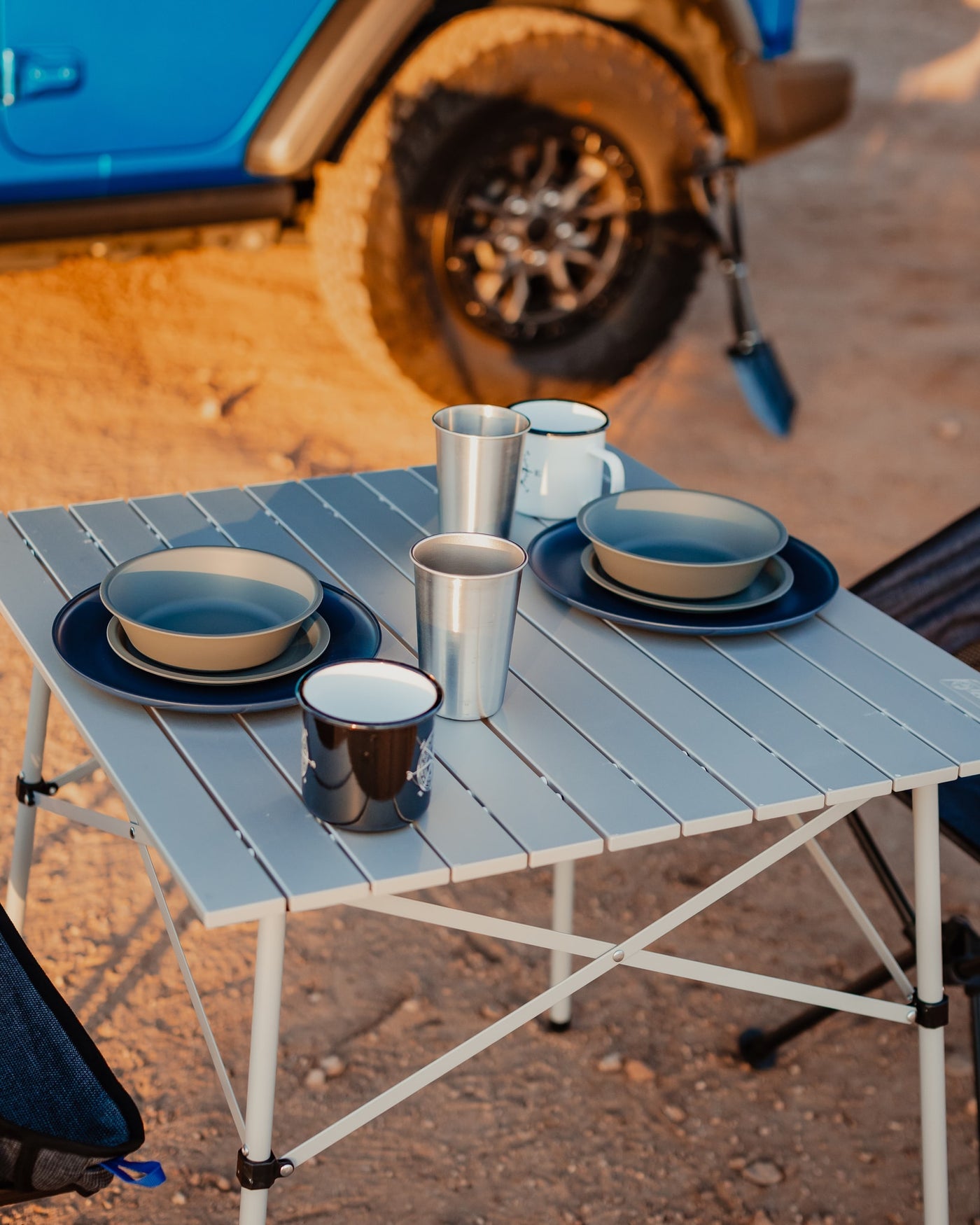 Portable table with dinnerware set for two, beside a blue vehicle in a desert landscape. Ideal for your RV rental trip. — photo 10