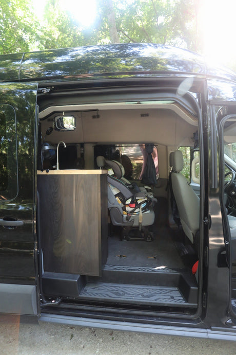 Spacious camper van interior for your next RV rental. Features a kitchen sink & child seat, ideal for family travel.