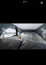 Cozy RV rental pop-top bedroom featuring a comfortable bed, a bright lantern, and a picturesque waterfront view. Perfect for camping!