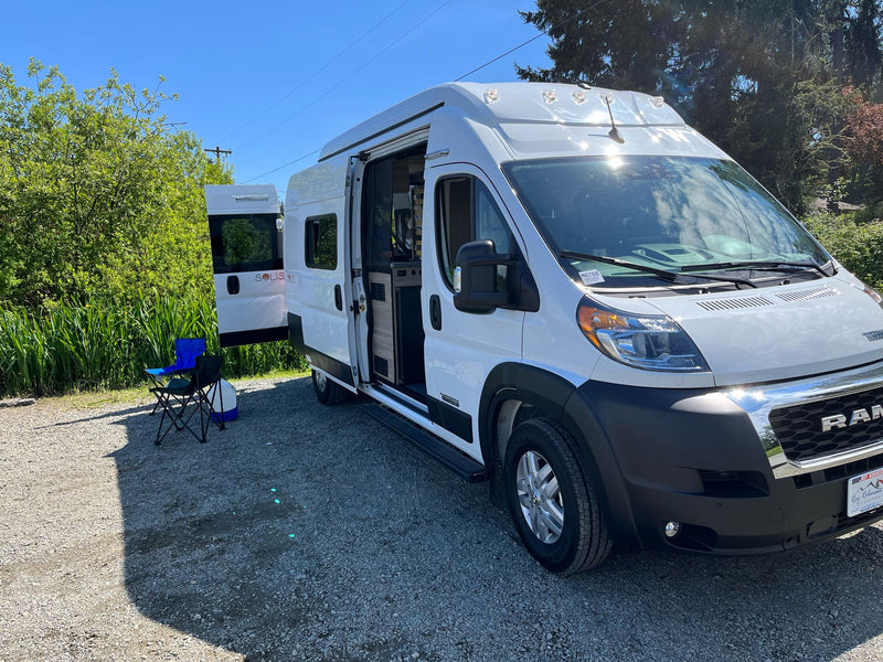  ready for adventure.|White Solis camper van RV rental parked on gravel with open door and chairs — photo 3