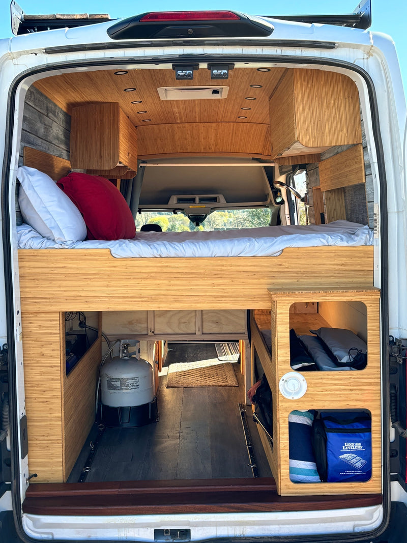 RV rental: Inside a modern camper van, featuring an elevated bed, bamboo wood interior, and functional under-bed storage. — photo 8