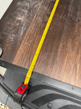 A tape measure laid across the worn wood-look floor of an RV rental, measuring the interior length above a vehicle step.