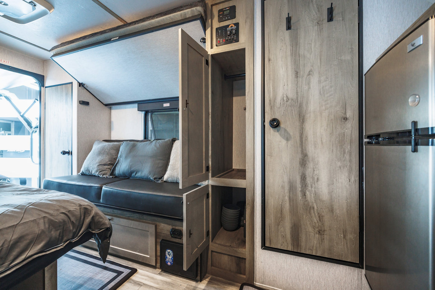 Inside this RV rental: a comfortable bed, sofa, overhead bunk, cabinet storage, and refrigerator, ready for your trip. — photo 19
