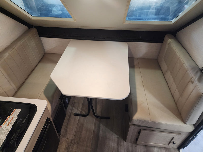 An RV rental's dinette area, showing comfortable benches, a white table, and skylights for a well-lit camper interior. — photo 9
