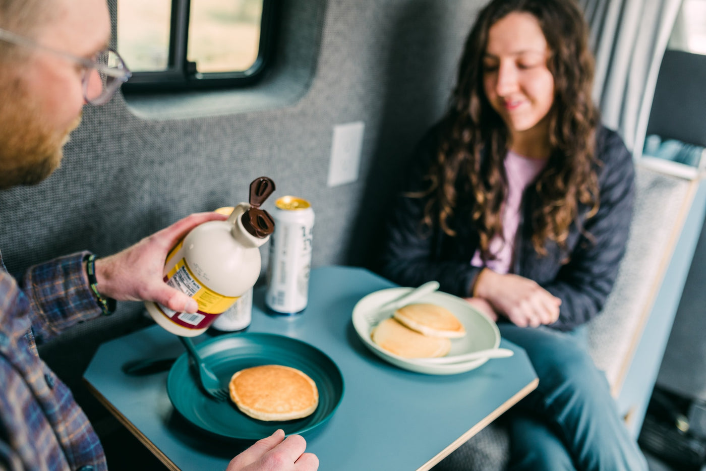 Inside an RV rental, a man pours syrup on pancakes as a woman smiles. Enjoying a mobile breakfast. — photo 18