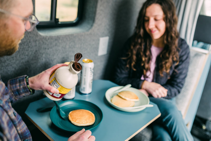 Inside an RV rental, a man pours syrup on pancakes as a woman smiles. Enjoying a mobile breakfast. — photo 18