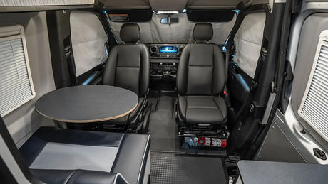 Inside a modern **rv rental** camper van, featuring flexible seating with swiveling front seats, a dining table, and bench area.