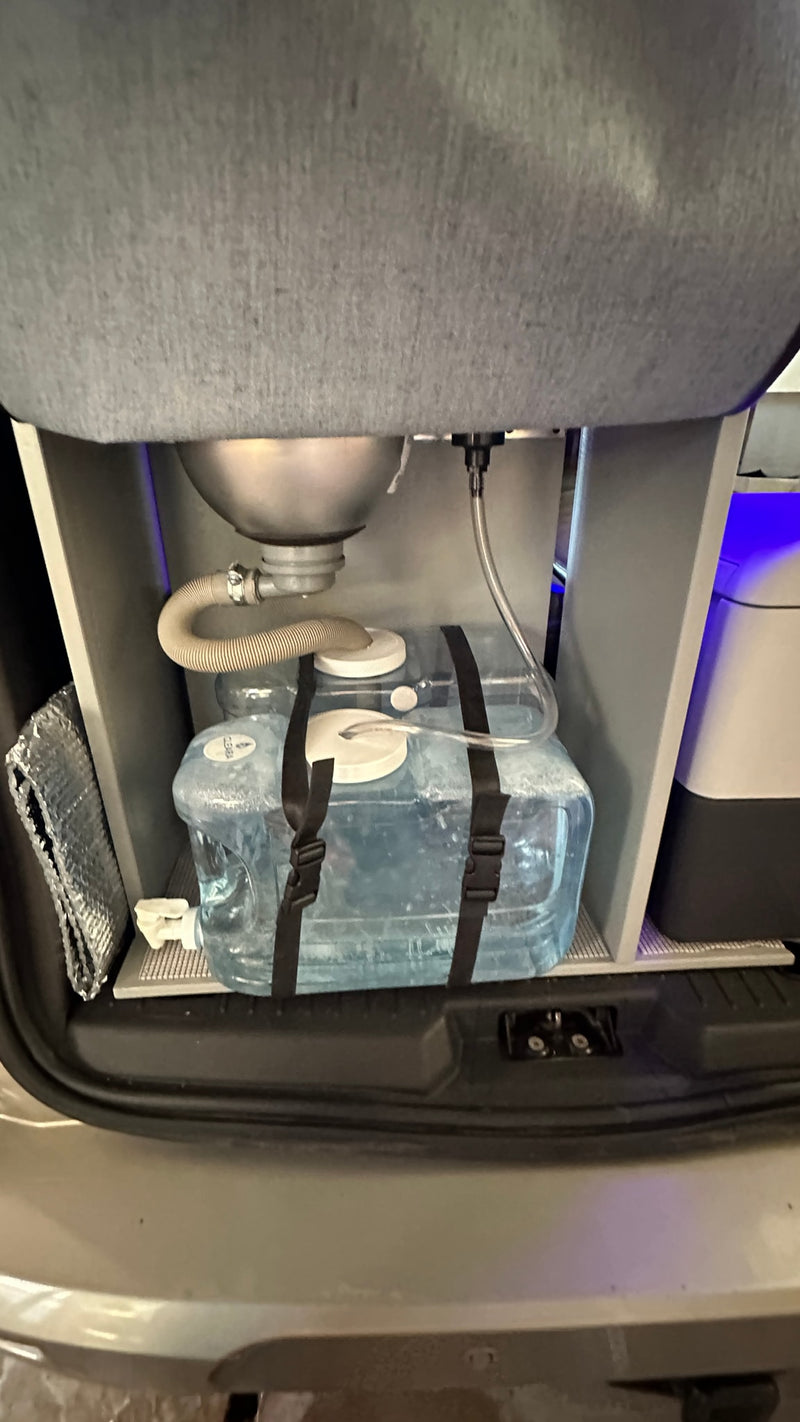 An rv rental's compact sink and water system, with clear fresh and greywater jugs below. Ideal for travel. — photo 13