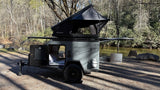 Compact Cedar Ridge Campers rv rental with a deployed ROAM rooftop tent by a serene river, perfect for outdoor adventure.