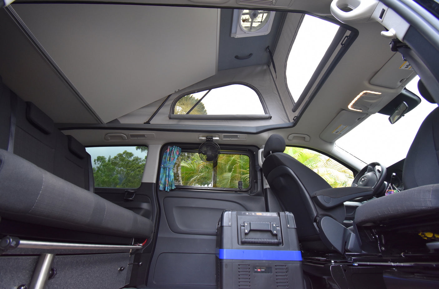 Spacious RV rental interior: pop-top bed, convertible rear seats/bed, and a portable cooler, ready for adventure.