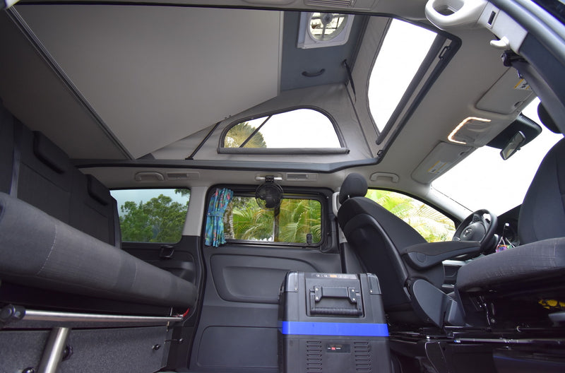  revealing a cozy bed and an ocean view through the front.|RV rental camper van interior: bed — photo 19