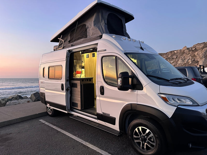 White Winnebago Solis rv rental parked by the ocean at sunset — photo 1