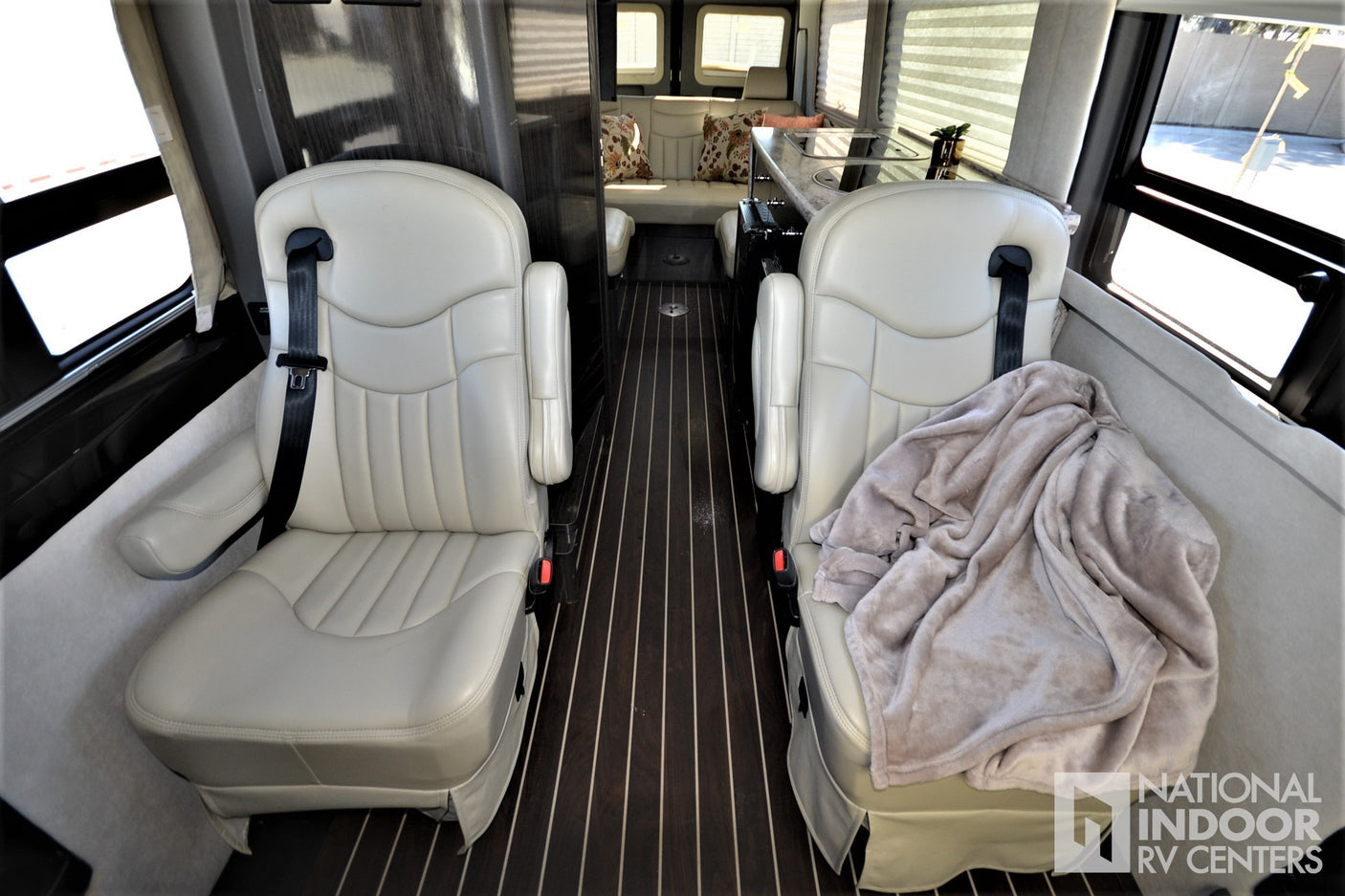Inside this **RV rental**: Comfortable captain's chairs, galley kitchen, and rear lounge provide a cozy travel space.