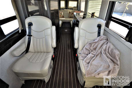 Inside this **RV rental**: Comfortable captain's chairs, galley kitchen, and rear lounge provide a cozy travel space.
