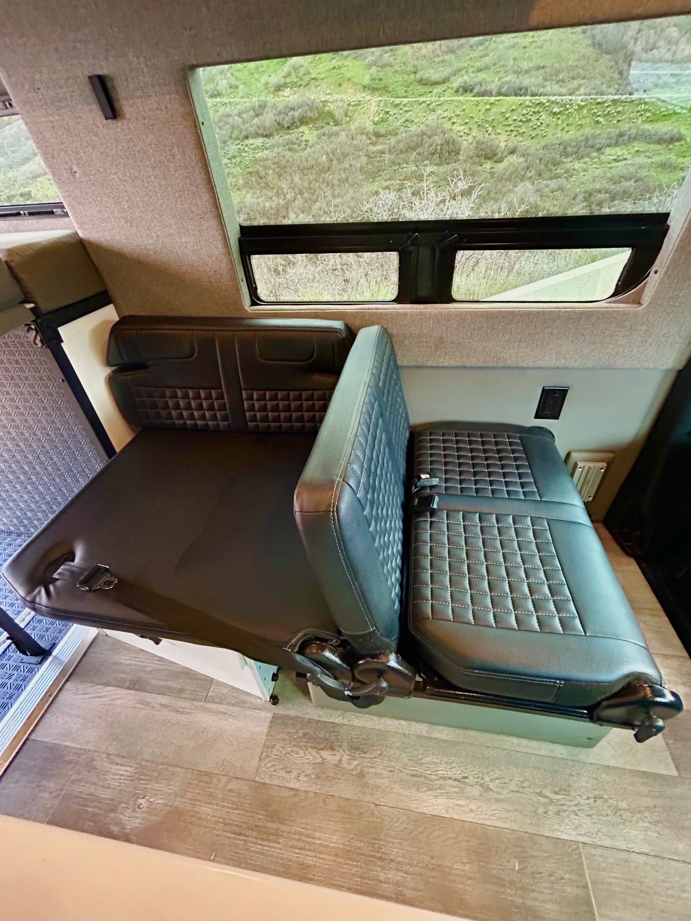 RV rental: Camper van interior with versatile seating that converts to a bed, offering scenic outdoor views.