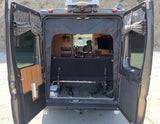 Open back of an RV rental: versatile interior with a bed, table, & storage for travel adventures.