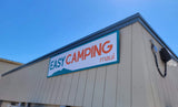 "Easy Camping Maui" sign for RV rental, displayed on a light building under a clear sky. Features a mountain design for your island camping.