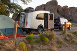 RV rental: Airstream Basecamp trailer & SUV parked in a rocky desert landscape beside a tent at sunset.