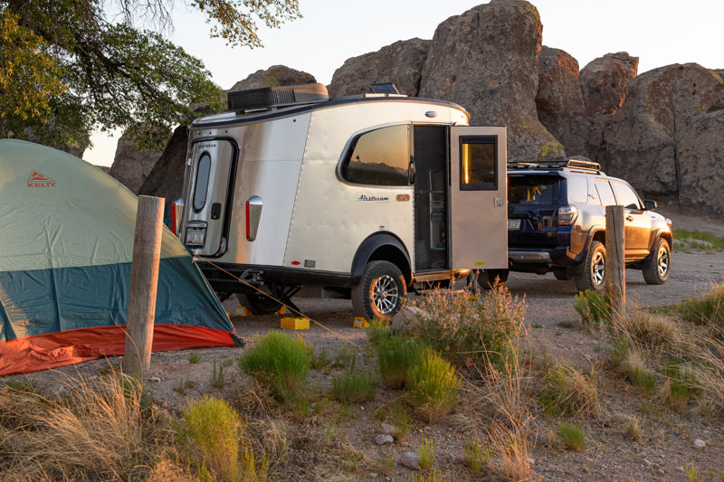 RV rental: Airstream Basecamp trailer & SUV parked in a rocky desert landscape beside a tent at sunset. — photo 14