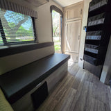 RV rental interior: cozy dinette, window with blinds, open door to outside, cabinets, and storage shelves.