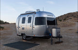 This Airstream travel trailer, a sleek silver RV rental, is perfectly set for dry camping on a quiet gravel lot.