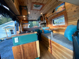 Stunning wood-paneled rv rental interior: kitchen, cozy seating, and bed. A complete mobile home adventure awaits!