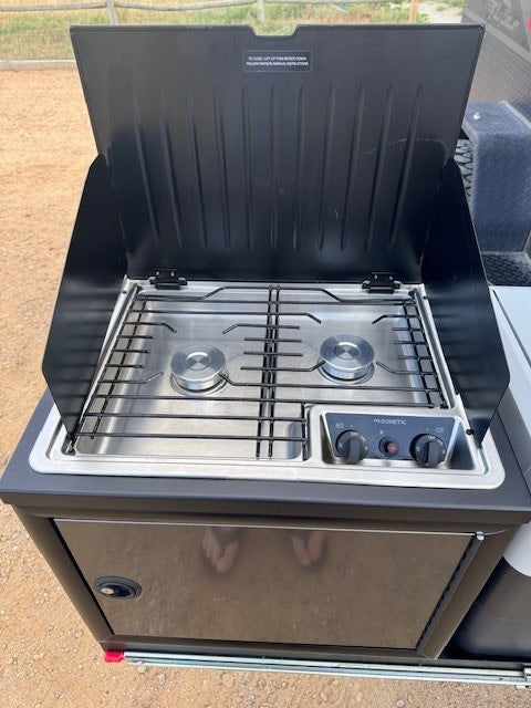 An open black Dometic outdoor kitchen unit with a two-burner stainless steel stove, often seen with an rv rental.